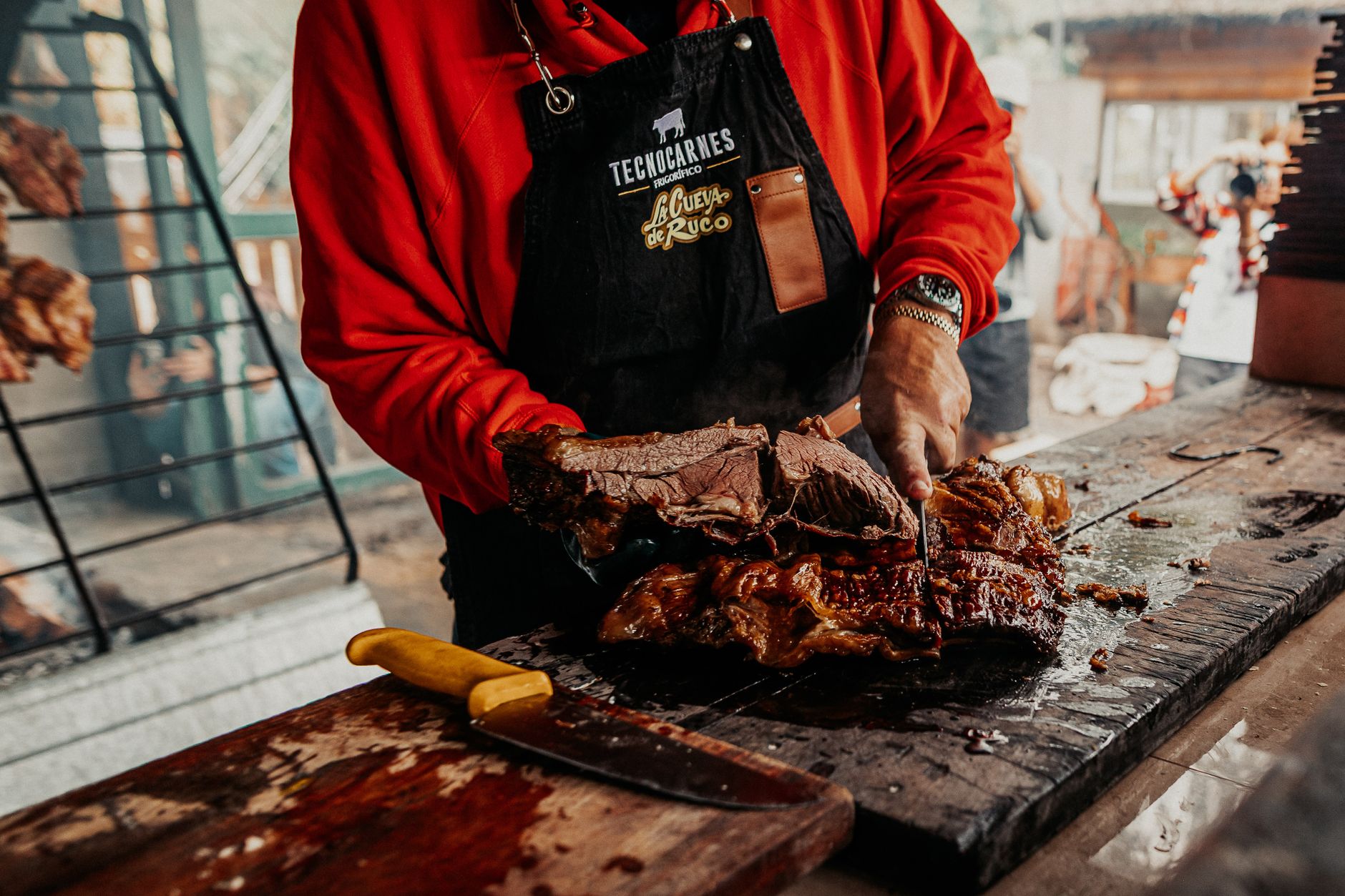 A cook preparing traditional Argentine asado with grilled beef slices in Provincia de Buenos Aires, Argentina.