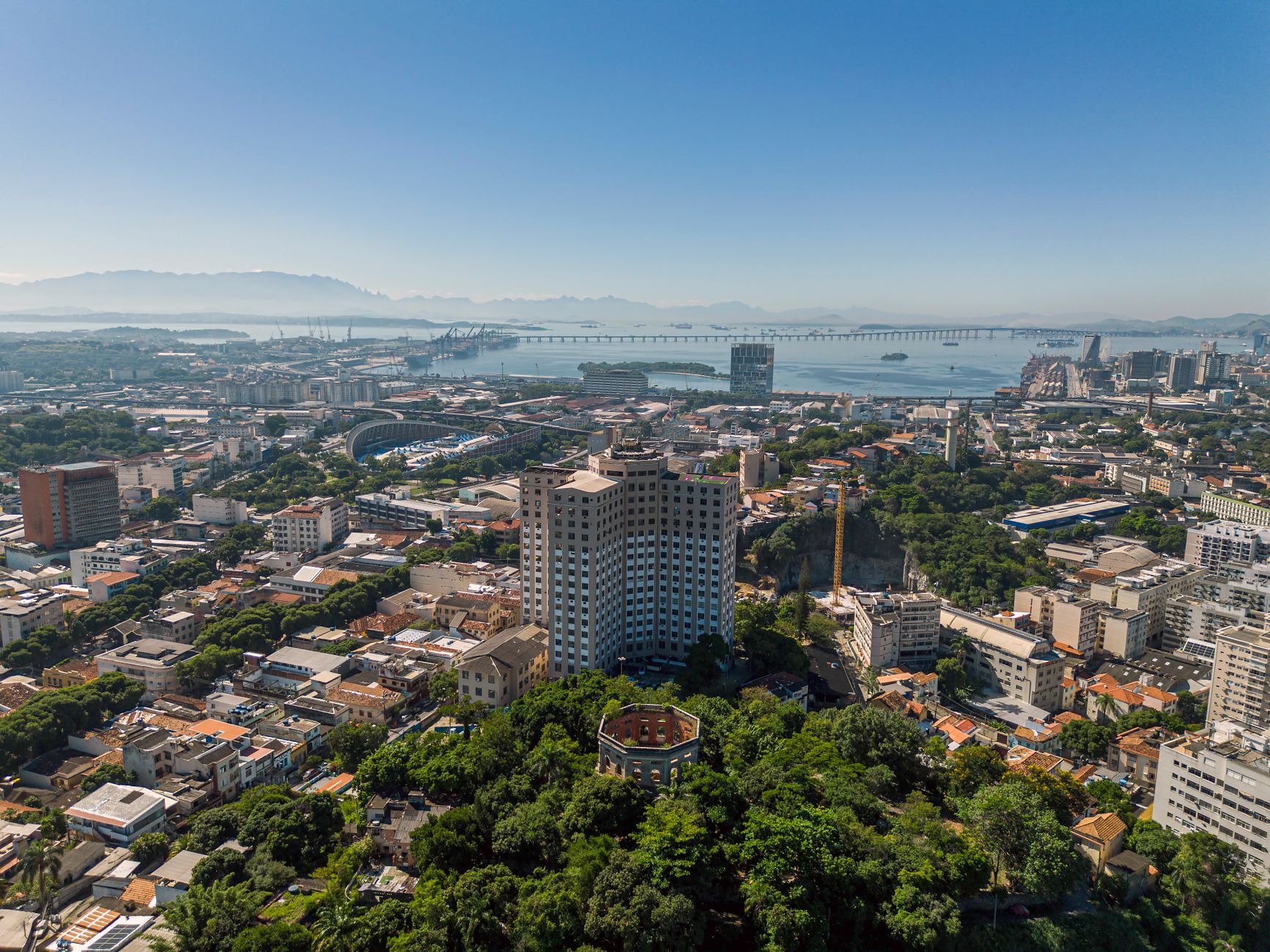 Stunning aerial view of Rio de Janeiro cityscape with prominent high-rises and vast greenery beneath a clear blue sky.