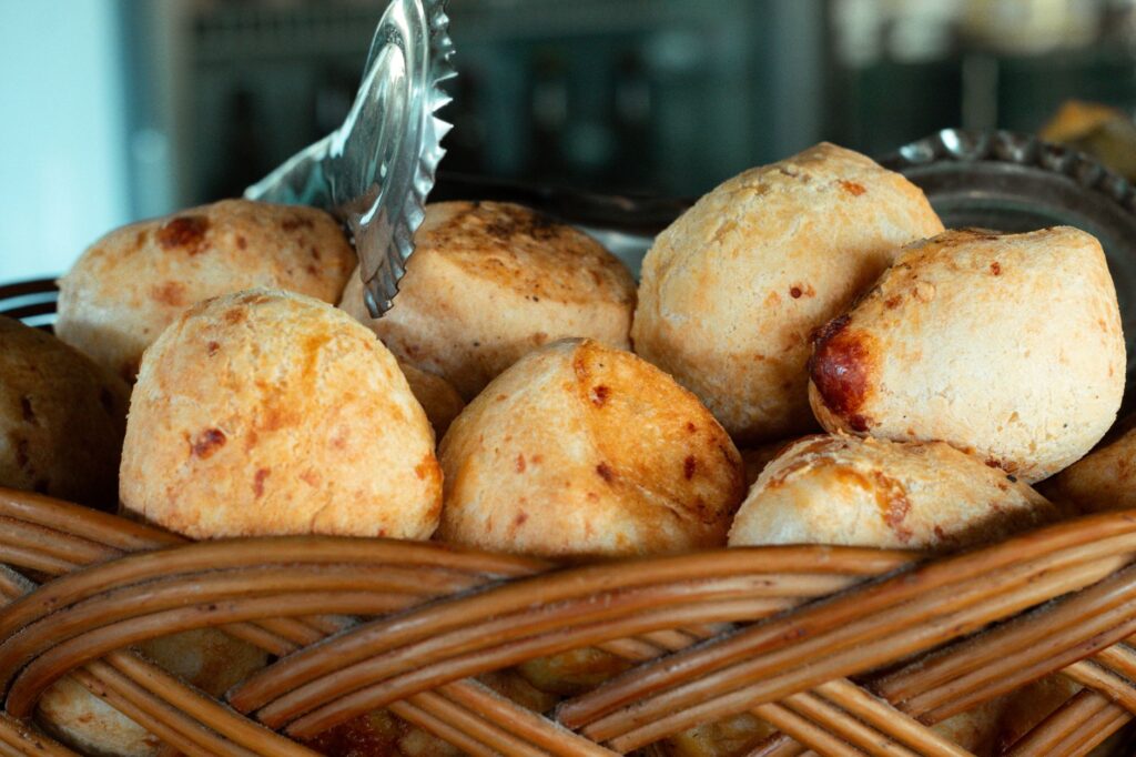 Close-up of freshly baked pão de queijo, a popular Brazilian cheese bread, in a woven basket.
